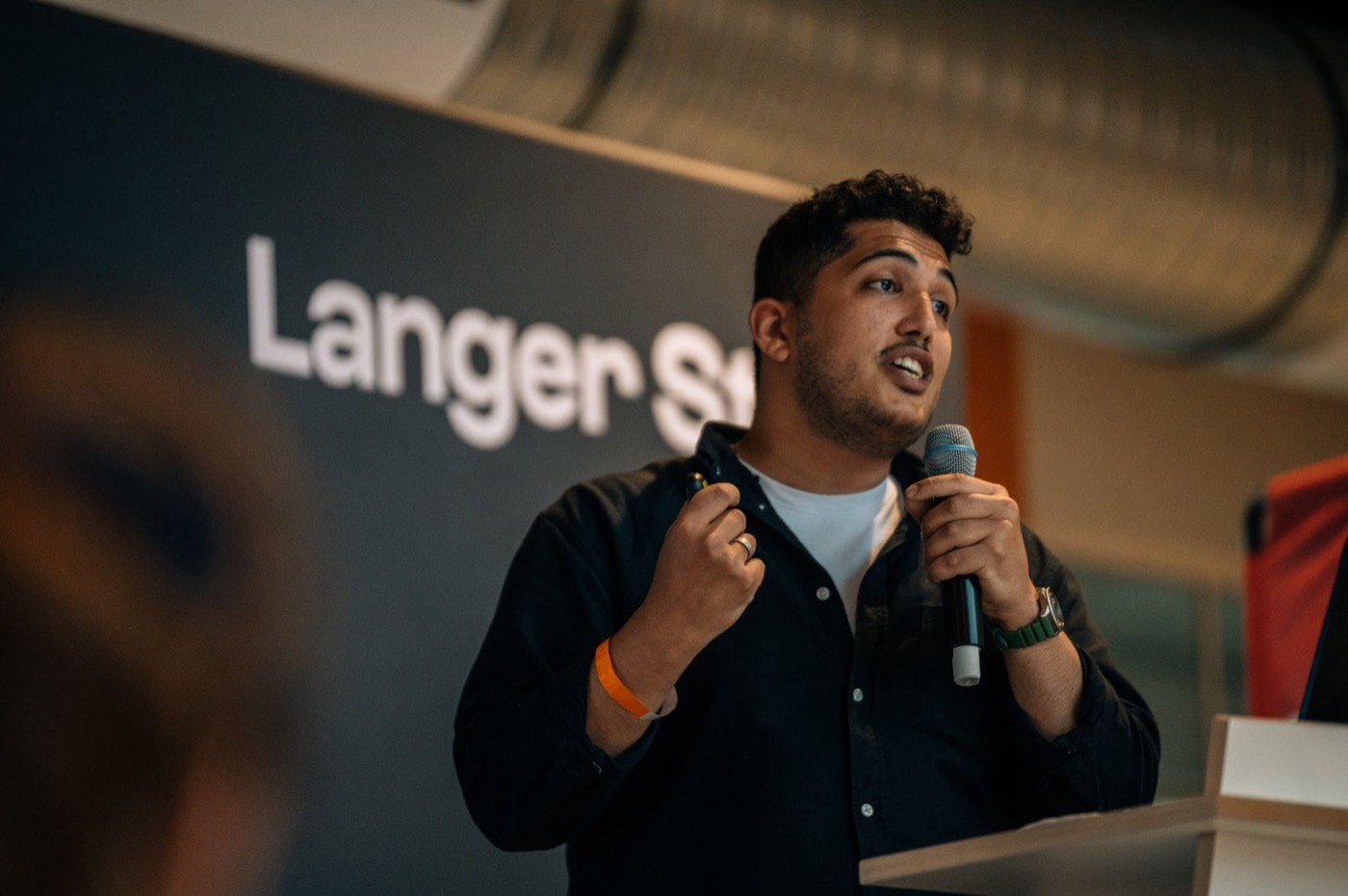 Abdullah Zeyn speaking on stage with a microphone in Potsdam